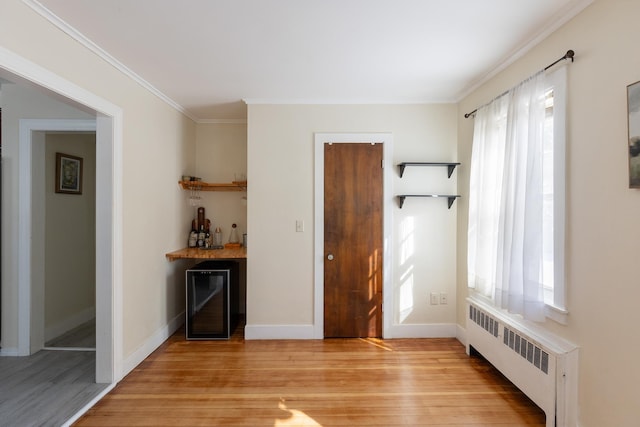 interior space featuring a healthy amount of sunlight, a dry bar, light wood-type flooring, and radiator heating unit