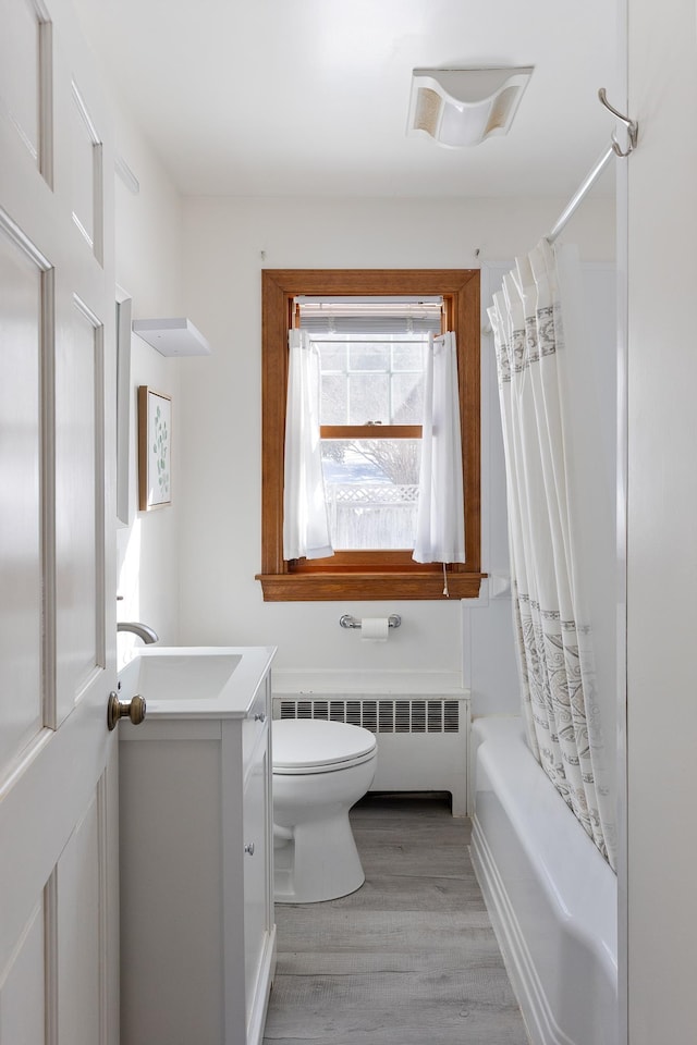 full bath with shower / bath combo with shower curtain, toilet, radiator heating unit, wood finished floors, and vanity