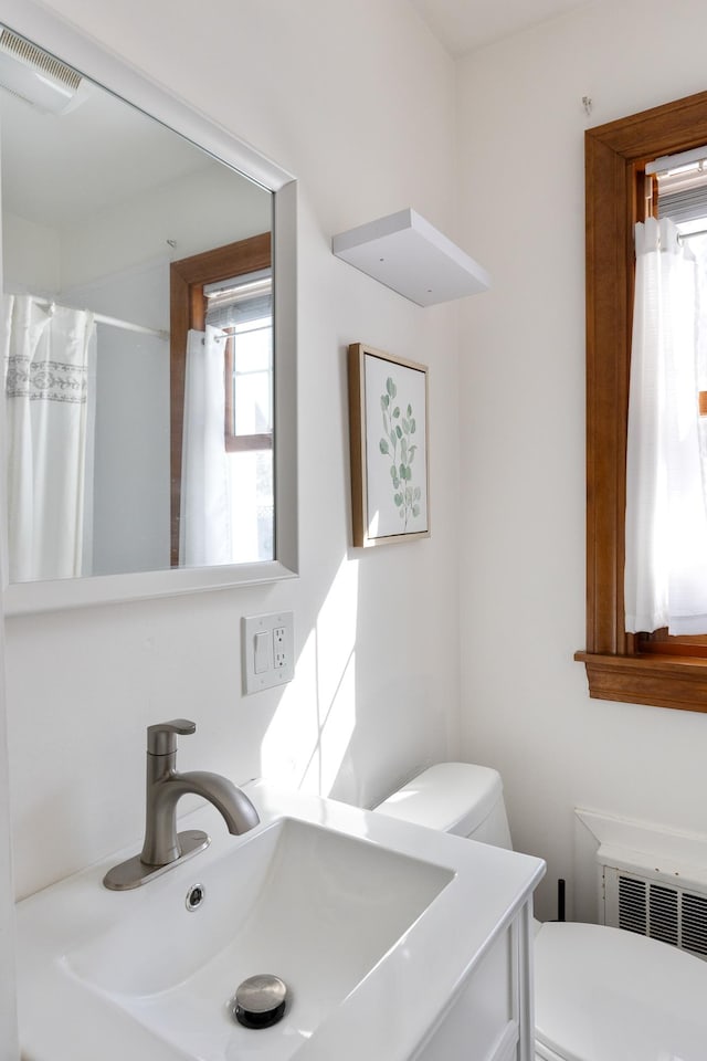 bathroom with vanity, a shower with curtain, visible vents, radiator heating unit, and toilet