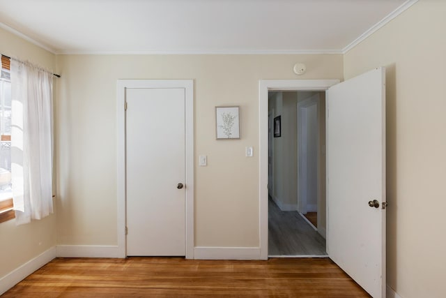 unfurnished bedroom with light wood-style flooring, baseboards, and ornamental molding