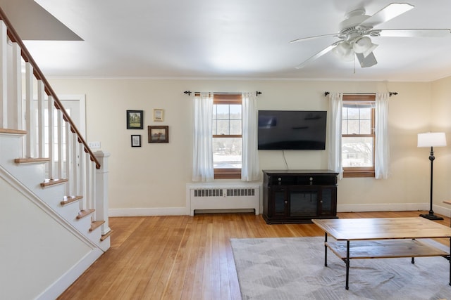 living room with radiator, crown molding, baseboards, stairway, and wood-type flooring