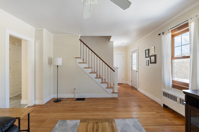 entryway featuring visible vents, radiator heating unit, stairs, light wood-style floors, and crown molding