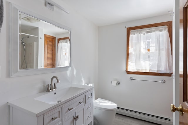 bathroom featuring a wealth of natural light, vanity, toilet, and a baseboard heating unit