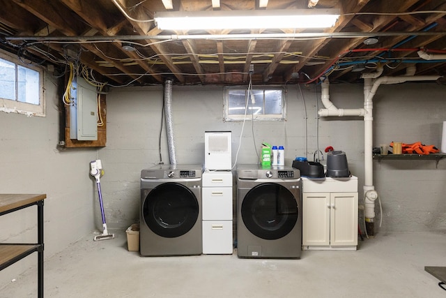 washroom with washer and clothes dryer, cabinet space, and electric panel