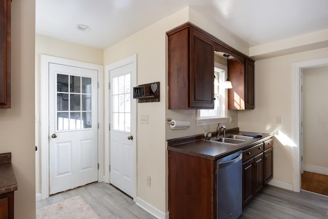 kitchen featuring dark countertops, dark brown cabinets, light wood-style flooring, stainless steel dishwasher, and a sink