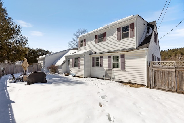 snow covered rear of property with fence