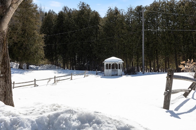 yard layered in snow featuring a gazebo and a forest view