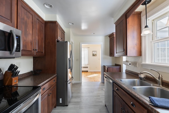 kitchen with a sink, dark countertops, appliances with stainless steel finishes, and radiator heating unit