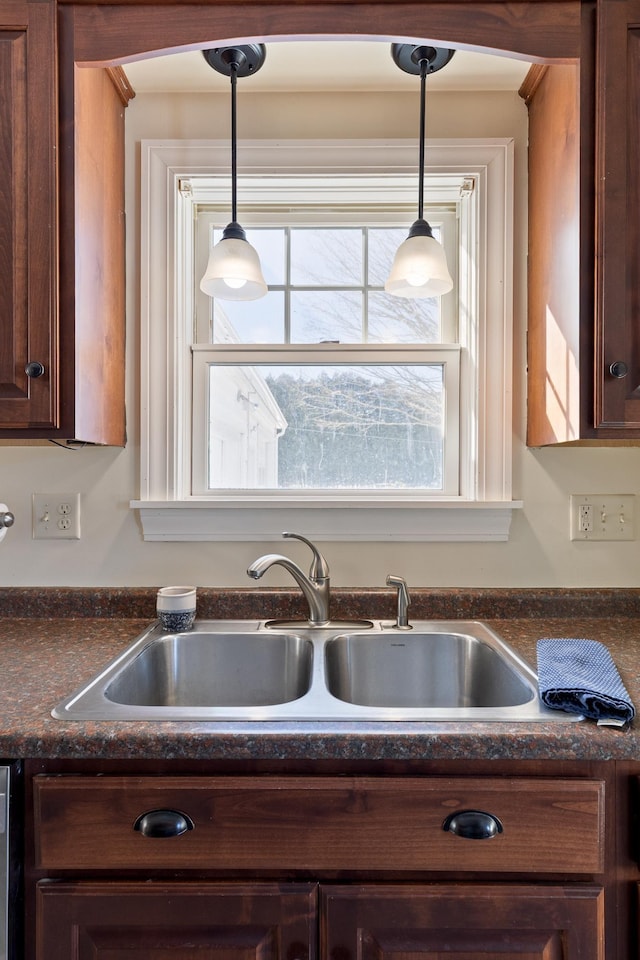 kitchen with dark countertops, hanging light fixtures, and a sink