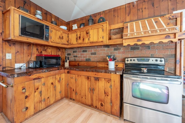 kitchen with dark countertops, black microwave, brown cabinets, light wood-style floors, and electric range