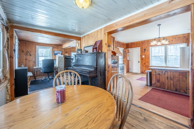 dining room featuring plenty of natural light, wooden walls, and light wood finished floors