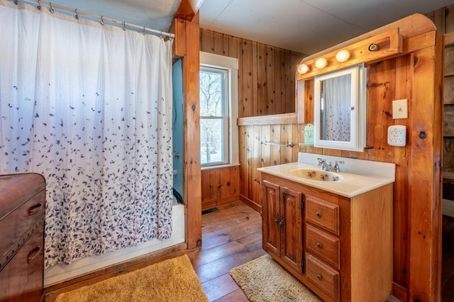 full bath featuring hardwood / wood-style floors, vanity, visible vents, and wood walls