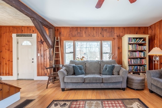 living room with hardwood / wood-style floors, wooden walls, visible vents, and ceiling fan