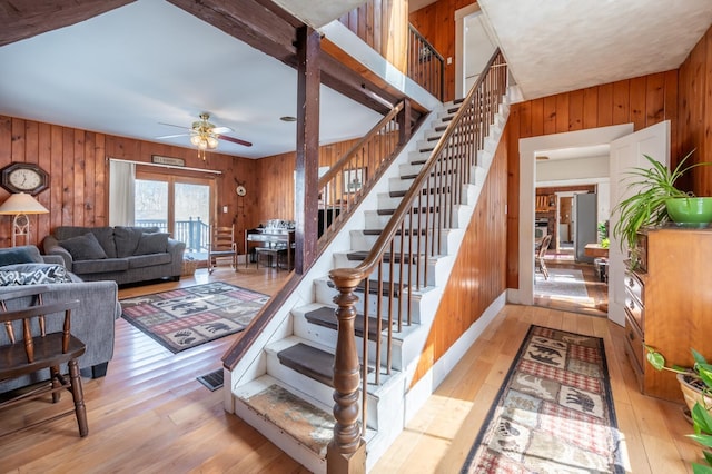 stairs with ceiling fan, visible vents, hardwood / wood-style floors, and wood walls