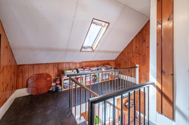 additional living space featuring lofted ceiling with skylight and wooden walls