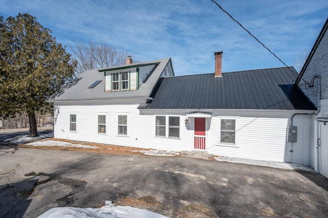 back of property with metal roof and a chimney