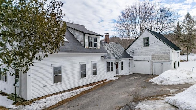 back of property with driveway and a chimney