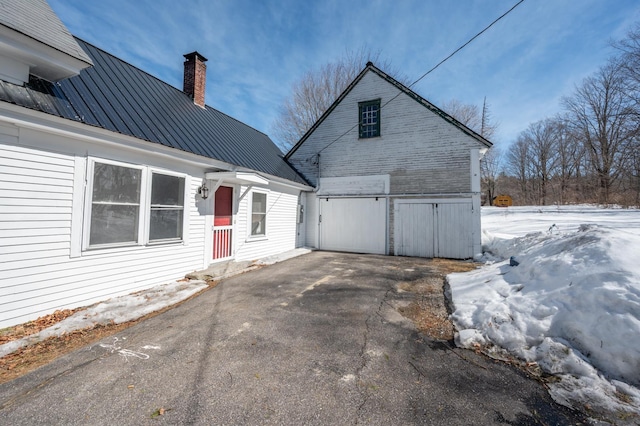 exterior space with metal roof, driveway, and a chimney