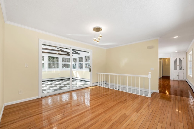 empty room featuring crown molding, wood-type flooring, baseboards, and a baseboard radiator