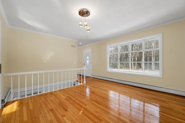 unfurnished room featuring a notable chandelier, crown molding, light wood-type flooring, and a baseboard radiator