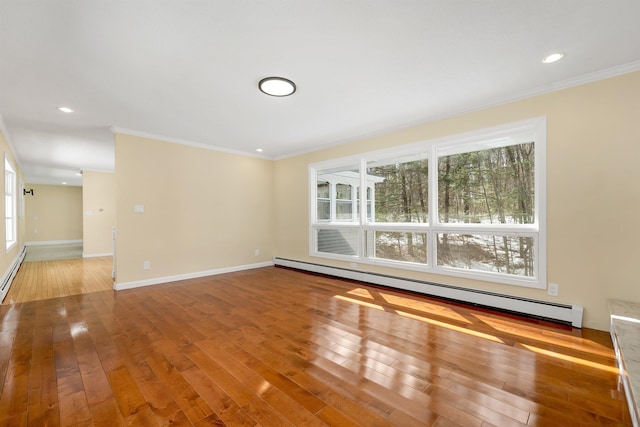 empty room featuring baseboard heating, crown molding, baseboards, and hardwood / wood-style floors