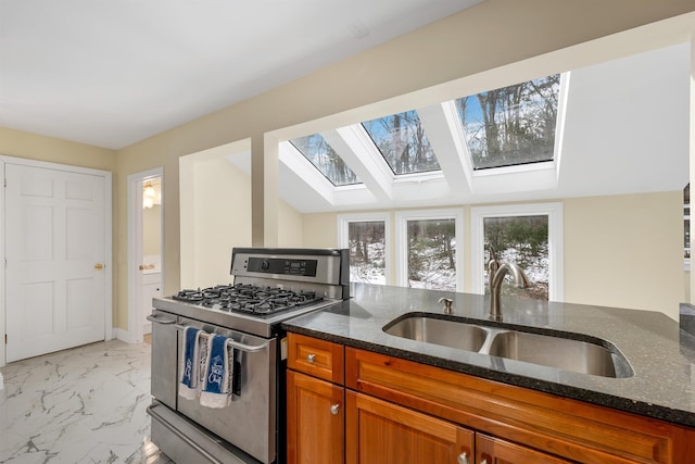 kitchen featuring a sink, stainless steel gas stove, marble finish floor, and brown cabinetry