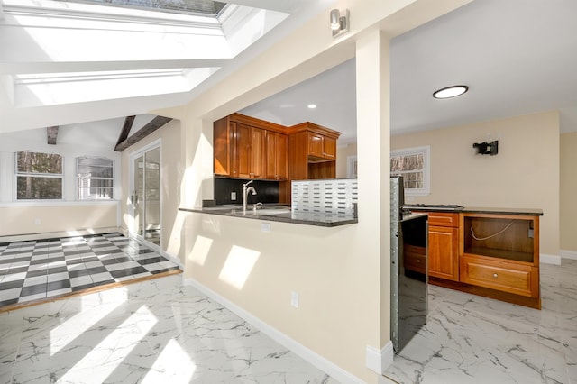 kitchen with dark countertops, tasteful backsplash, baseboards, brown cabinets, and marble finish floor