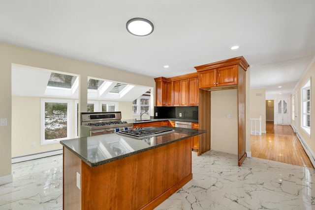 kitchen with marble finish floor, plenty of natural light, appliances with stainless steel finishes, a skylight, and baseboard heating