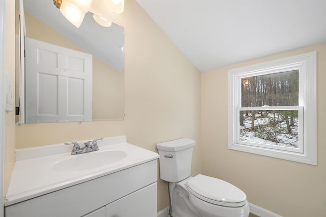 bathroom with vanity, vaulted ceiling, toilet, and baseboards