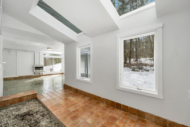 interior space with baseboards, heating unit, and lofted ceiling with skylight