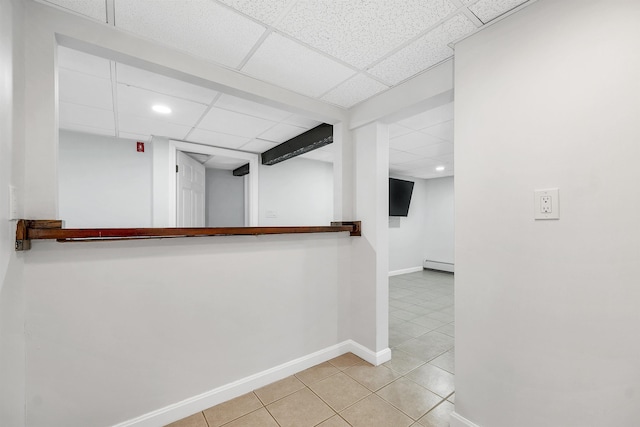 hallway with tile patterned flooring, a drop ceiling, baseboards, and a baseboard radiator