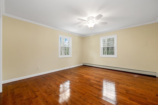 unfurnished room with a baseboard heating unit, ornamental molding, a wealth of natural light, and hardwood / wood-style floors