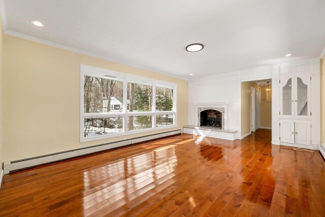 unfurnished living room featuring a fireplace with raised hearth, crown molding, a baseboard radiator, recessed lighting, and wood-type flooring