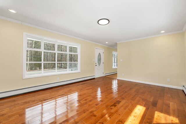 unfurnished living room with crown molding, a baseboard heating unit, baseboards, and wood finished floors