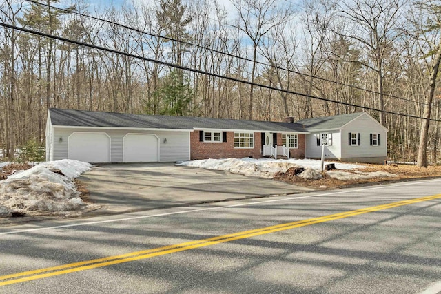 single story home featuring a garage, brick siding, a chimney, and aphalt driveway