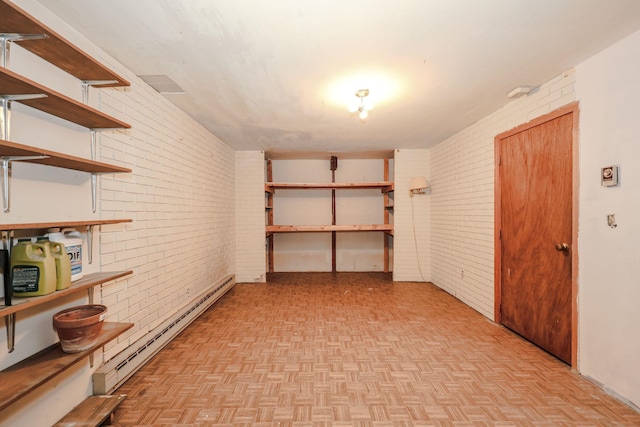 interior space with a baseboard heating unit and brick wall