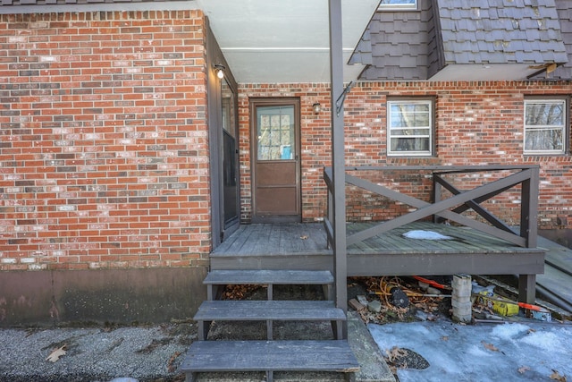 property entrance featuring mansard roof and brick siding