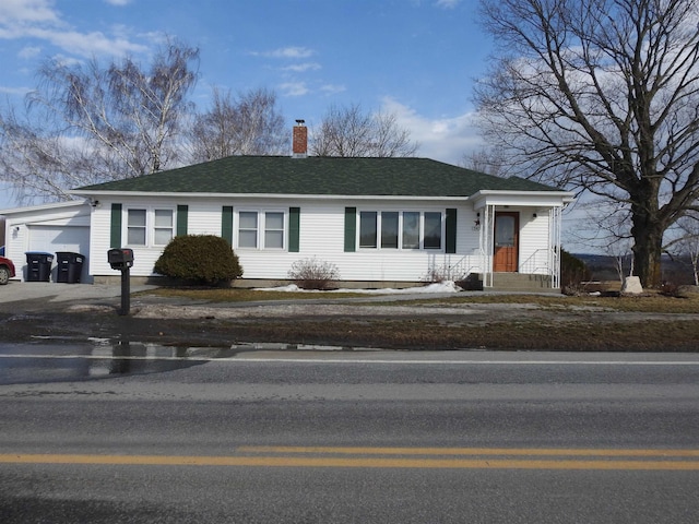 single story home featuring a garage, a chimney, and roof with shingles