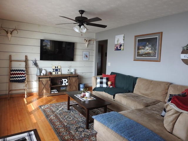 living area featuring light wood-style flooring, a textured ceiling, and a ceiling fan