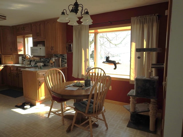 dining space featuring a notable chandelier, baseboards, light floors, and a healthy amount of sunlight