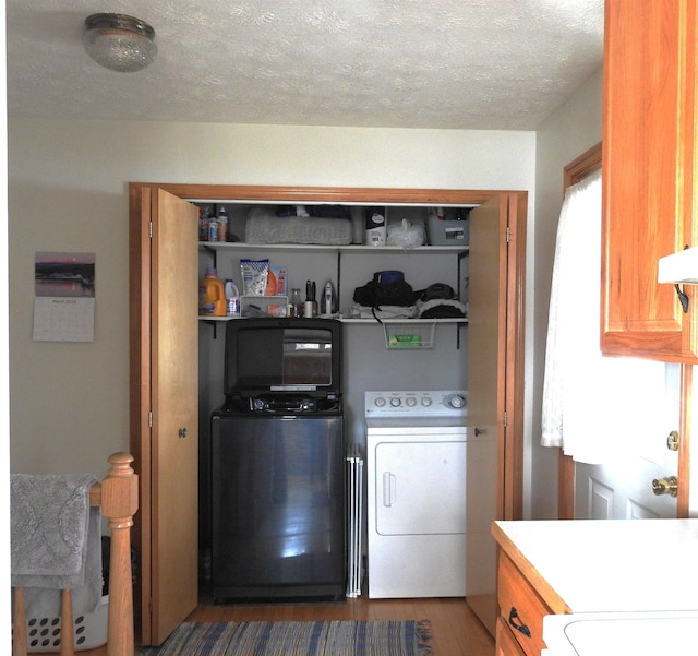 clothes washing area featuring laundry area, a textured ceiling, wood finished floors, and separate washer and dryer