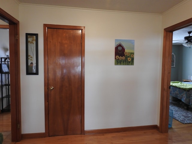 hall featuring baseboards, wood finished floors, and ornamental molding