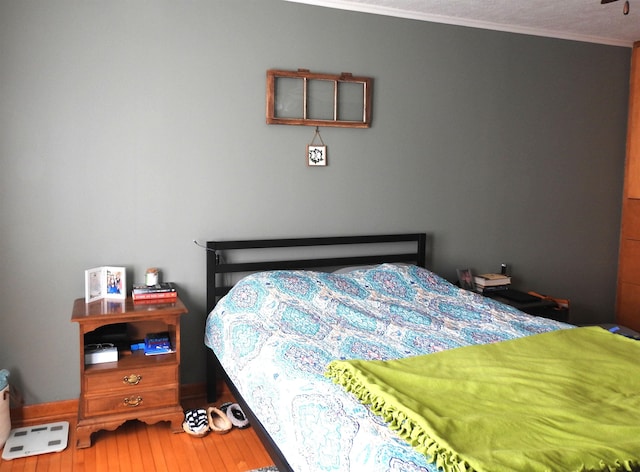 bedroom with crown molding and wood finished floors