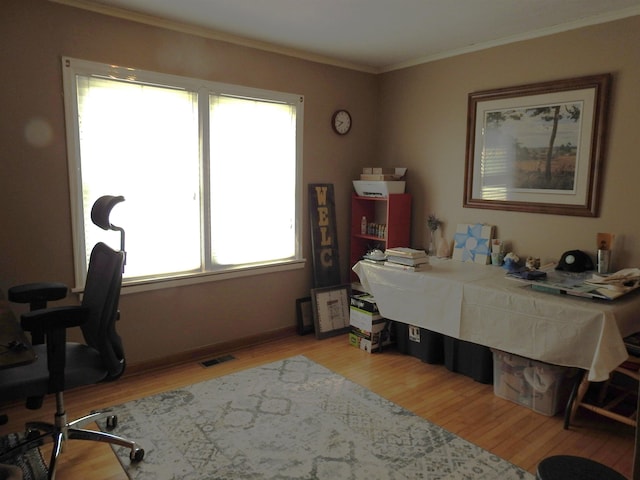 home office featuring visible vents, light wood-style flooring, and ornamental molding