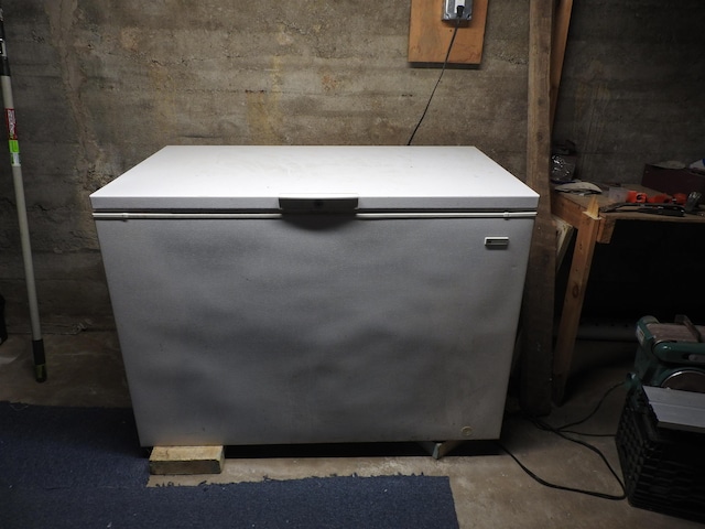 details featuring fridge and unfinished concrete flooring