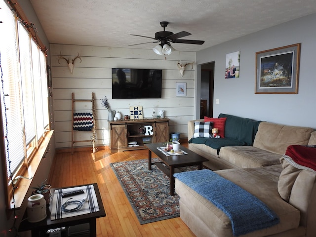 living room with a textured ceiling, ceiling fan, and hardwood / wood-style flooring