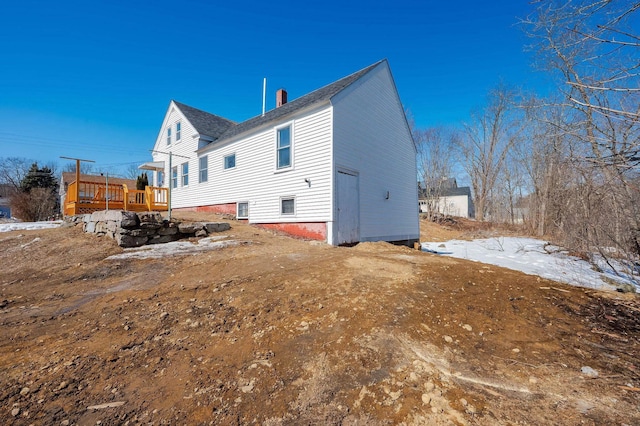 rear view of property featuring a wooden deck and a chimney