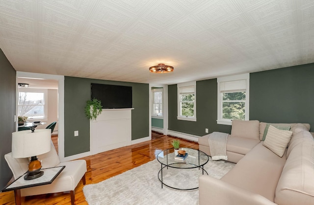 living room featuring a baseboard heating unit, baseboards, and wood finished floors