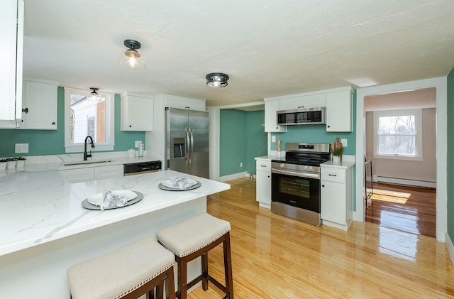 kitchen with plenty of natural light, white cabinets, stainless steel appliances, and a sink