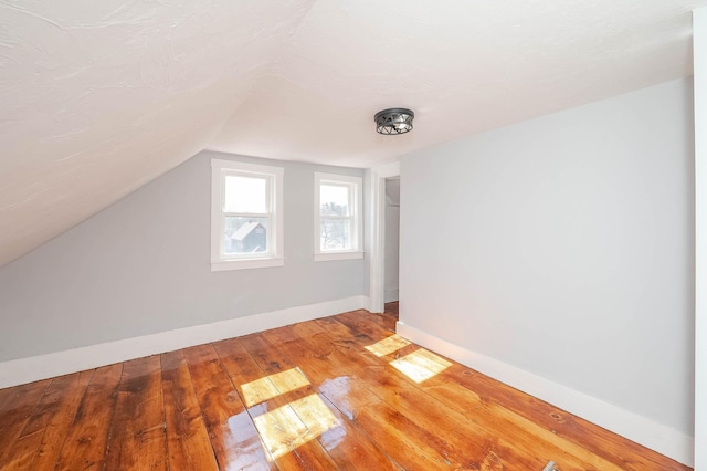 bonus room featuring baseboards, vaulted ceiling, and hardwood / wood-style flooring